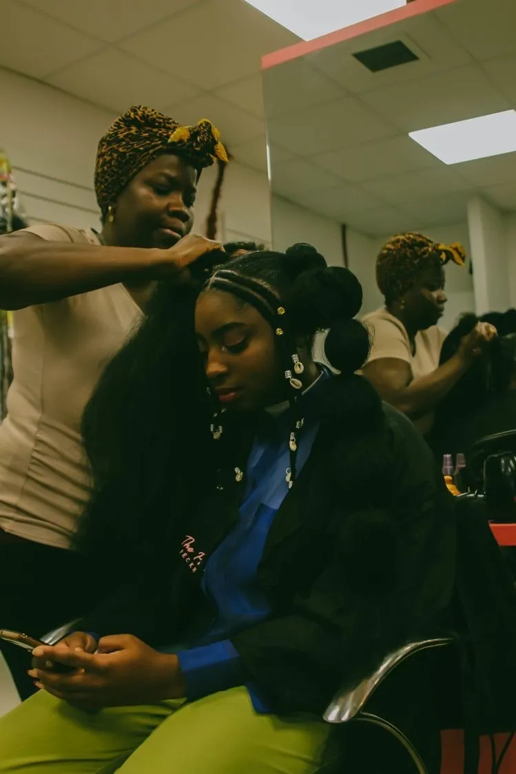 A braider working on a client's hair in a salon